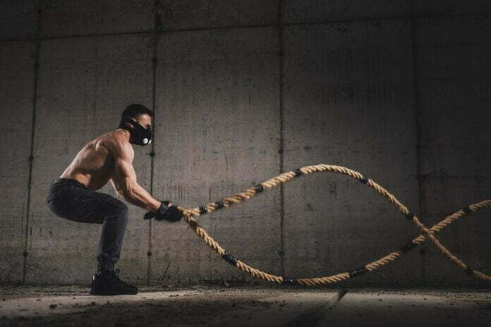 A picture containing man doing a battle rope, a type of cardio exercise